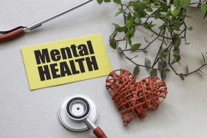 MENTAL HEALTH word on a small yellow piece of paper next to a st